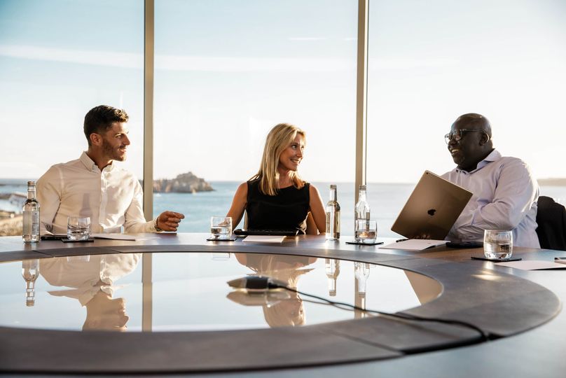Businesspeople sitting at desk chatting in meeting room