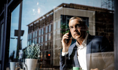 Man in a suit speaks on his phone inside a café.