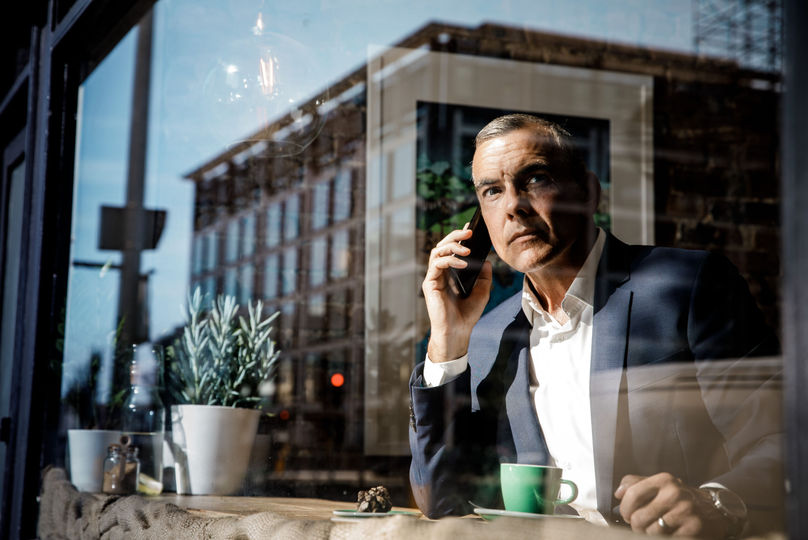 Man in a suit speaks on his phone inside a café.