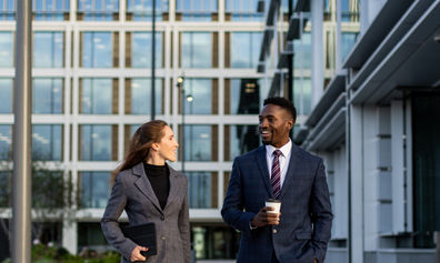 Two professionals walking side by side through a business district.