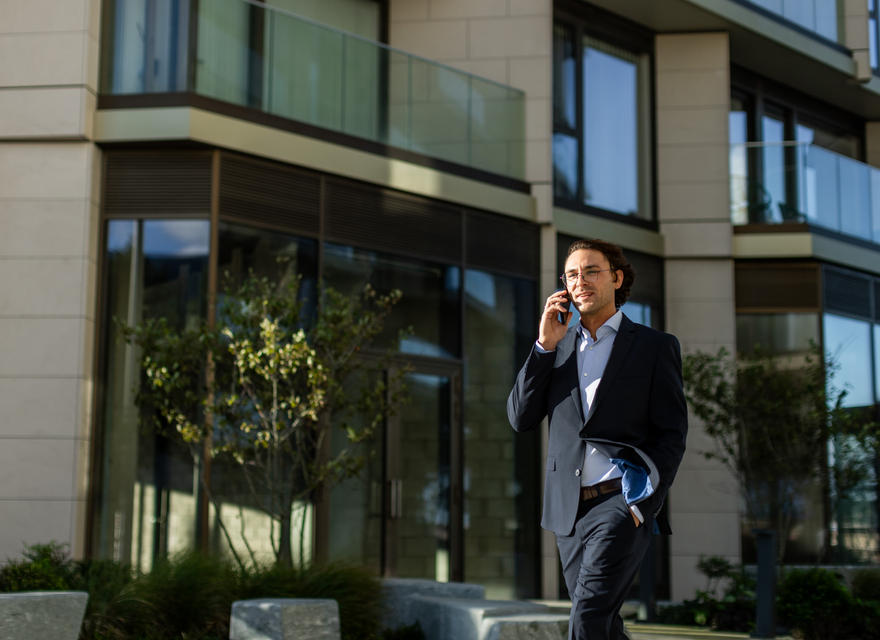 Man walking while on a phone call outside an office building