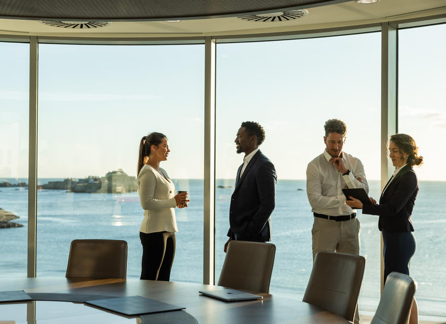 A professional meeting in an office with a stunning seaside backdrop.