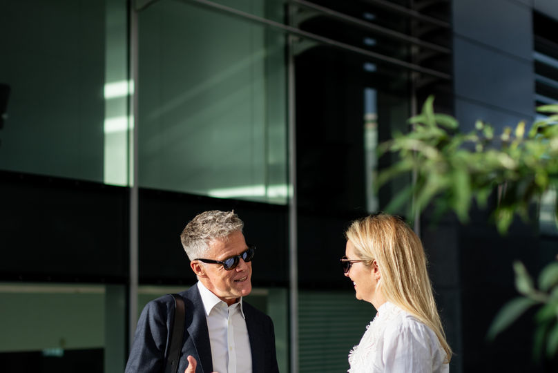 Casual conversation in front of a modern office building.