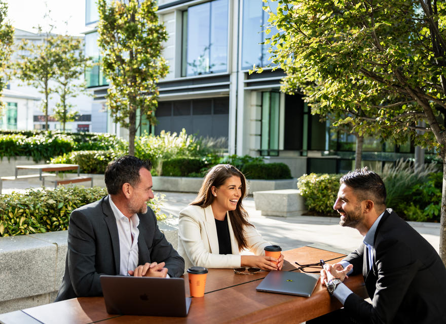 Three professionals sharing coffee outdoors