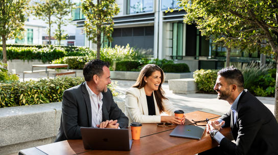 Three professionals sharing coffee outdoors