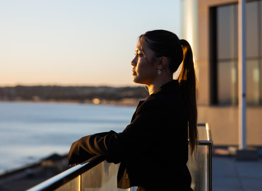 Portrait shot of a professional woman overlooking the sea at sunset, exuding confidence and focus.