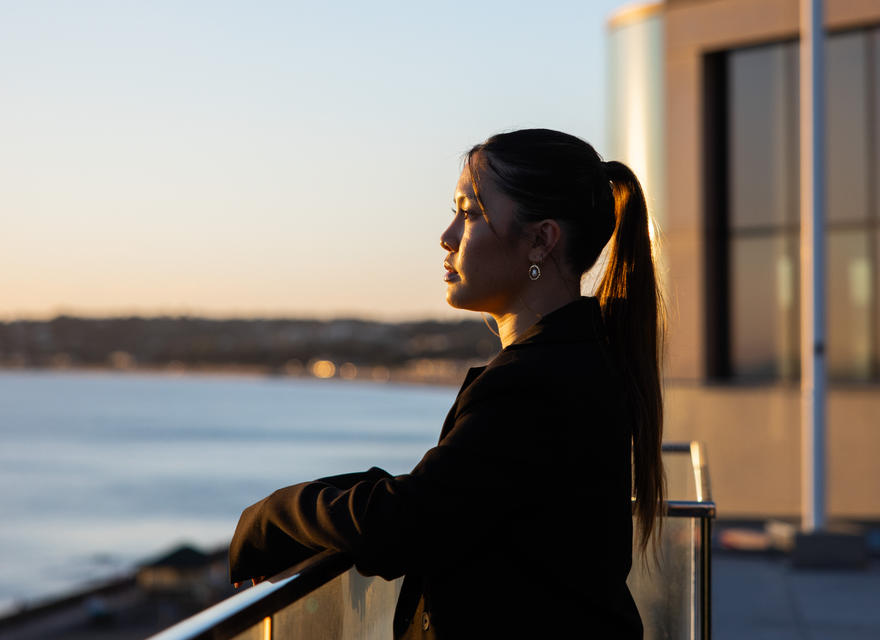 Portrait shot of a professional woman overlooking the sea at sunset, exuding confidence and focus.