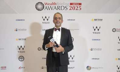 Faizal Bhana holding Jersey's Best IFC award in front of a screen of various logos
