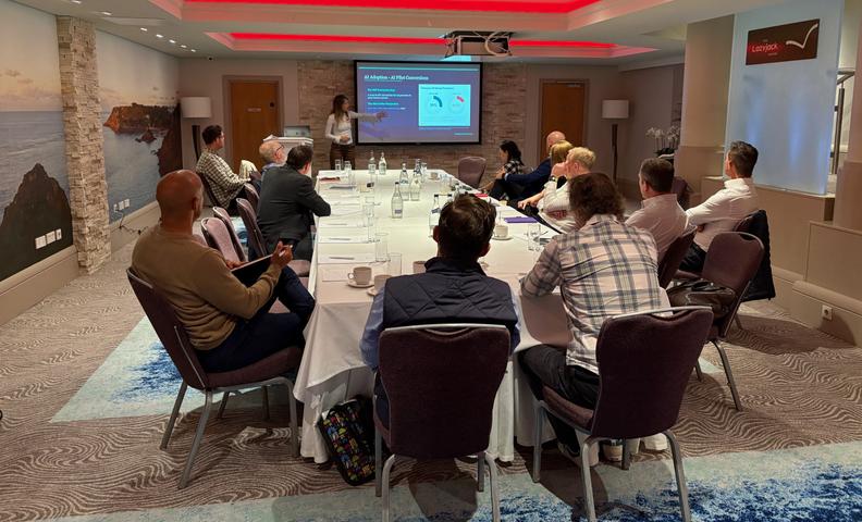 table with attendees watching presentation at our Tech Connect event